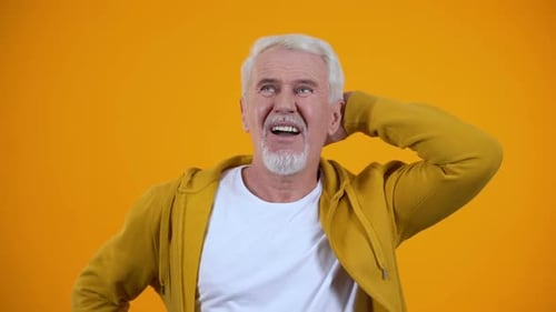 Senior Man Posing and Thinking on Orange Background