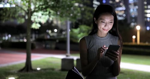 Woman Using Smartphone in Urban Park at Night