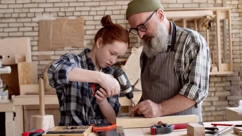 Child Learning Woodworking with Adult in Workshop