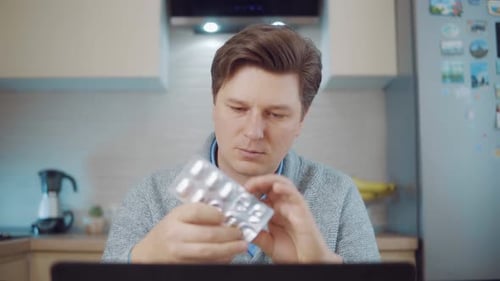 Man Takes Pill with Water in Kitchen