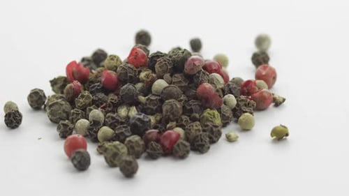 Pile of Mixed Peppercorns Rotating on White Surface