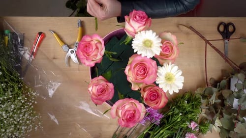 Vue de dessus des mains d'une jeune fleuriste créant une composition