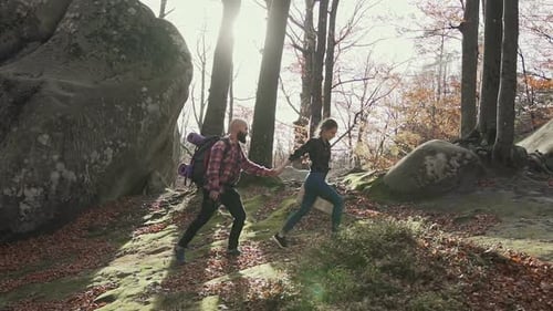Adventurous Couple Hiking Hand-in-Hand Through Autumn Forest