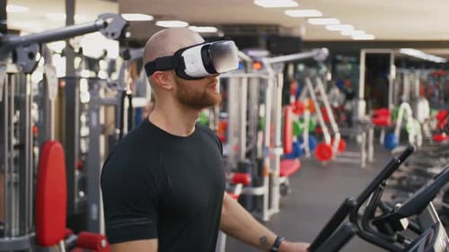 Young Strong Man Exercising on Treadmill at the Gym Wearing VR Glasses