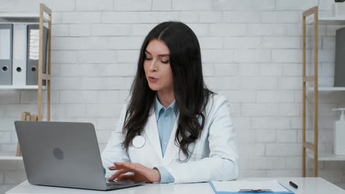 Female Doctor At Laptop Consulting Patient Online Sitting In Clinic