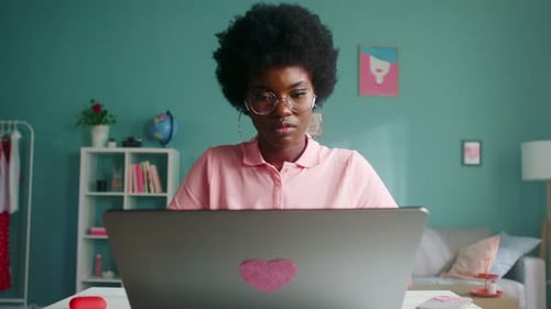 Woman Works on Laptop with Heart Sticker at Home