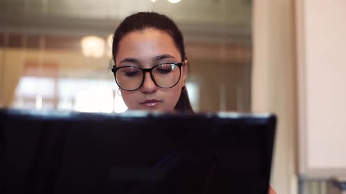 Business Woman in Glasses Works Using Computer Sitting at Table in Office