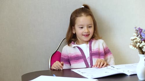 Girl Smiles and Flips Through Book at Table