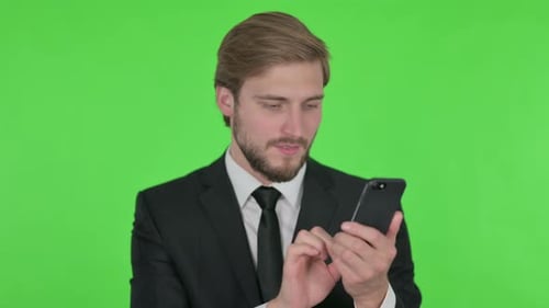 Young Businessman Browsing Smartphone on Green Background
