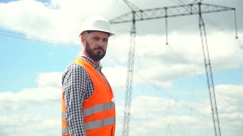 Engineer Wearing Hardhat Standing Near Electrical Towers