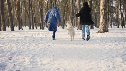 Happy Family Runs Through the Winter Snowy Forest with a Dog