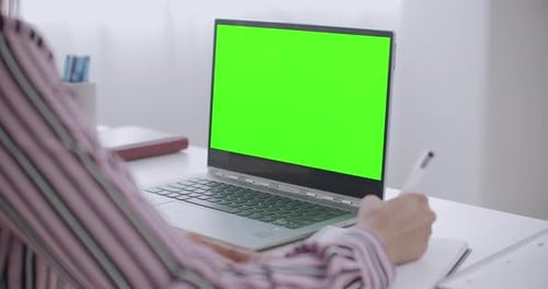 Woman Taking Notes with Laptop Green Screen