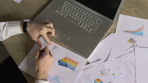 close up businessman working with documents charts and laptop