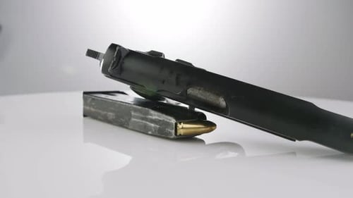Gun Control. 9mm handgun with bullets rotating on a reflective surface