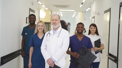 Portrait of Senior Doctor in White Uniform and Young Doctors Therapists Posing Looking at Camera