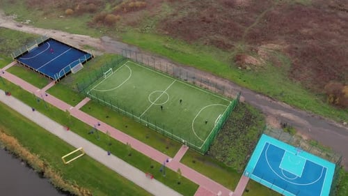 Green artificial soccer field on city quay, Football zone on promenade near river