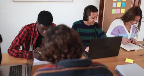 Multiracial students reading books and using laptop while studying together inside library