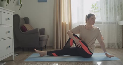 Sitting Young Woman Makes Yoga Stretching at Home