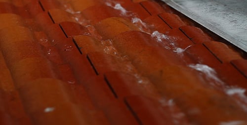 Water Flows Over Industrial Orange Tubes in a Row