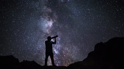 Photographe masculin prenant des photos et regardant le ciel étoilé de nuit dans les montagnes