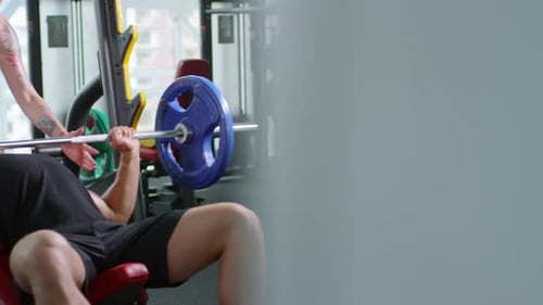 Man Bench Pressing with Female Trainer at Gym