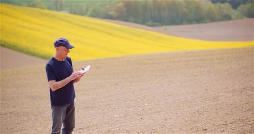 Agriculture Technology Concept - Farmer Examining Agriculture Field Working on Digital Tablet.