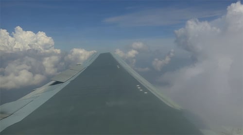 Airplane Wing Flying Above Puffy White Clouds