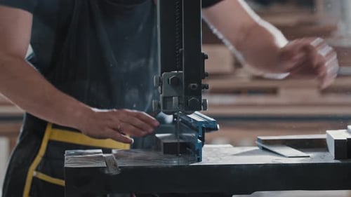 Man in a Carpentry Workshop Cutting a Small Pieces of the Wooden Detail Using a Cutting Machine