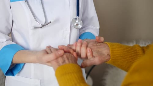 Doctor Comforts Senior Patient by Holding Hands