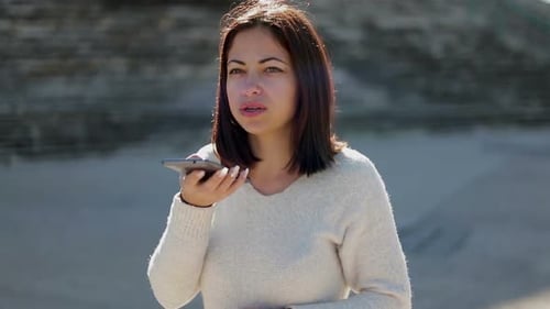 Woman Using Voice Message on Smartphone Outdoors