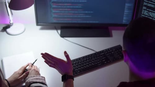 Two Colleagues Programmers are Sitting in Front of a Monitor and Typing Coding Language