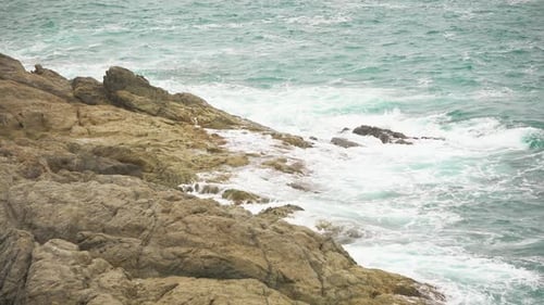Meereswellen brechen an der felsigen Küste. Schäumendes Wasser, das unruhige Meer