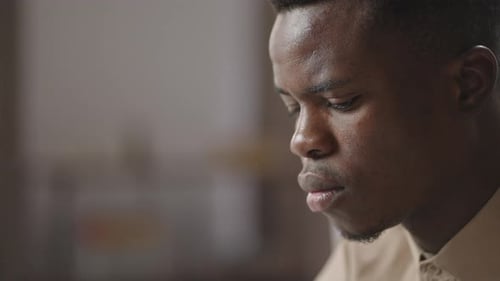 Konzentriertes Gesicht eines jungen schwarzen Mannes, der mit PC im Raum arbeitet Nahaufnahme Afroamerikanischer Student oder