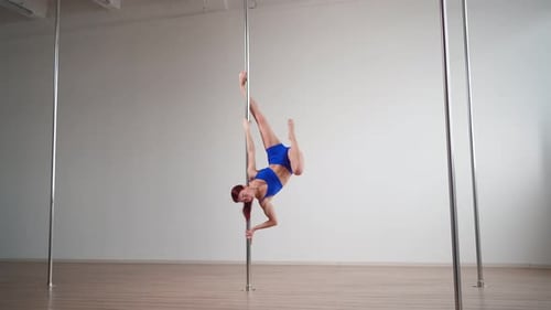 Woman Demonstrates Pole Fitness Moves in Studio