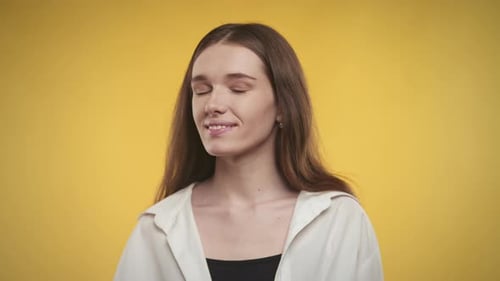 Close Up Portrait of a 20s Young Adult Woman in a White Shirt on a Bright Yellow Background