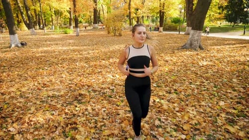Slow Motion Video From High Point of Beautiful Young Woman in Leggings Jogging at Autumn Park and