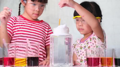 Young Girls Conducting Colorful Science Experiment Indoors