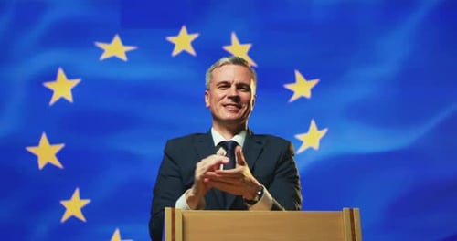 Smiling Man Gives Speech with EU Flag Backdrop