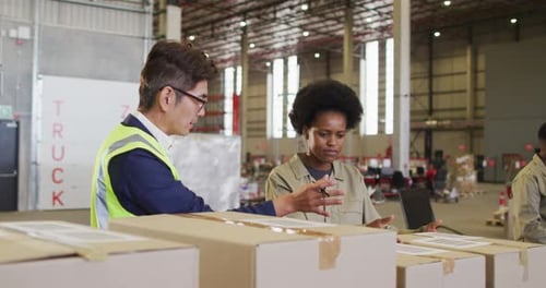 Diverse male and female workers with boxes talking in warehouse