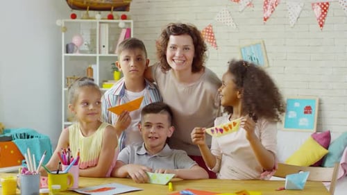 Teacher and Children Displaying Paper Crafts