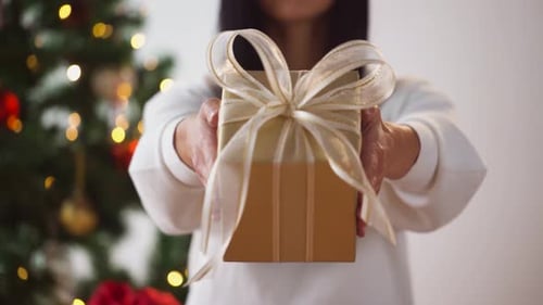 Woman Holds Out Beautiful Gold Christmas Gift
