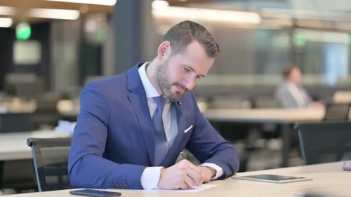Man Writing in Modern Office Environment