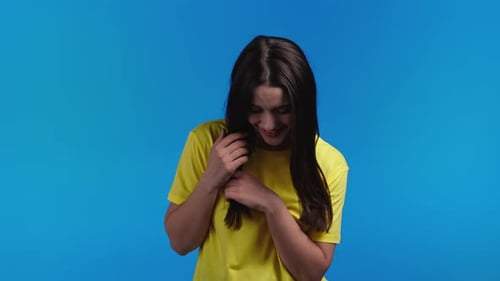 Smiling Brunette Posing in front of a Blue Background