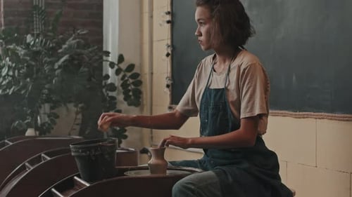 Woman Shapes Clay Vase on Pottery Wheel