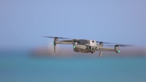 Drone Hovering Over Beach and Ocean