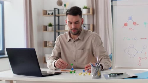Man Explains Molecule Model Near Laptop and Whiteboard