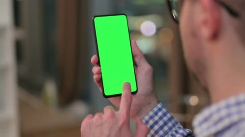Rear View of Young Man Holding Smartphone with Chroma Key Screen