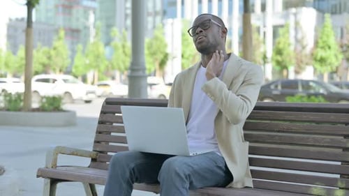 Man Massaging Neck while Working on Laptop