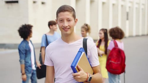 Student Smiling at Camera Against College