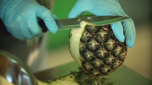 Gloved Hands Skillfully Cutting a Pineapple